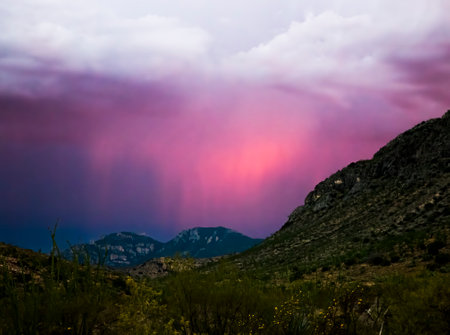 Rain bands under clouds blaze with pink light at sunset in an Arizona landscape.の写真素材