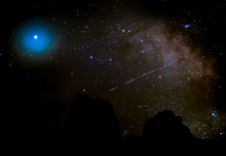 Milky Way with comet shooting through in desert night sky with mountain silhouette on horizon.の写真素材