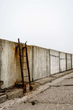 Rusty metal ladder on stone pierの写真素材