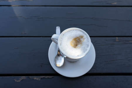 Cup of coffee with milk, on wooden table in black colorの写真素材
