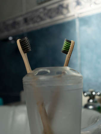 Two bamboo toothbrushes in a light blue bathroomの写真素材