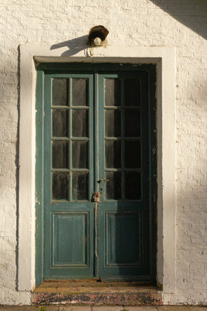Old wooden door on a white wall in the village of Ponta Delgada, Portugalの写真素材