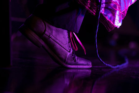 close up of man foot in leather shoes on black background with neon lightの写真素材