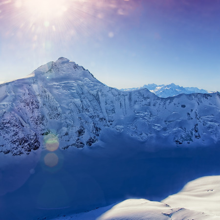 Mountain peak at Swiss Aletch glacier helicopter view in winterunder bright sunshineの写真素材