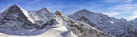 Panorama of four alpine peaks (Jungfrau, Eiger, Monch and Tschuggen) and skiing resort in swiss alps