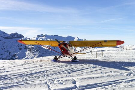 Yellow red airplane at the mountain airfield in swiss alps in front of alpine ridgeのeditorial素材