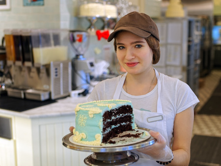 Young girl with creamy cake at the bakery