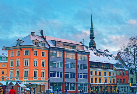 RIGA, LATVIA - DECEMBER 28, 2014: Old buildings in the heart of Rigas beautiful Old Town. Evening view with blue cloudy sky and the steeple of the St Peters Church in background. Riga, Latvia, Baltic, Europeのeditorial素材