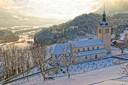Winter in Switzerland. Picturesque snow-covered mountain landscape near the castle of the Gruyeres with an old church in the foreground.のeditorial素材