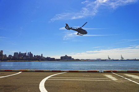 New York, USA - April 25, 2015: Black Helicopter over from helipad in Lower Manhattan in New York, USA, on East River. Pier 6. East River and skyscrapers of Brooklyn on the backgroundのeditorial素材