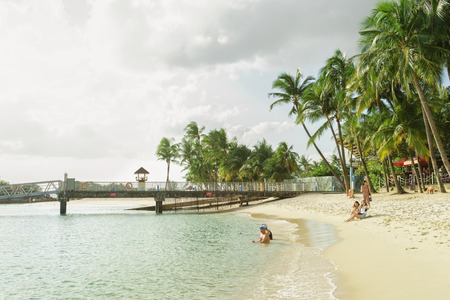 Singapore, Singapore - March 1, 2016: People swimming at Siloso Beach at Sentosa island resort in Singapore. It is an artificial beach with a sand taken from Malaysia and Indonesia.のeditorial素材