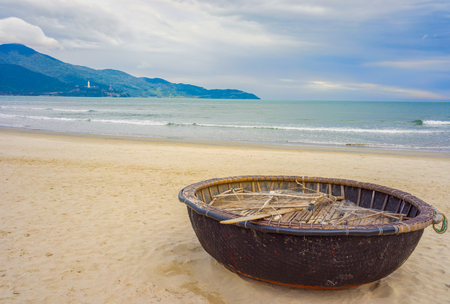 Mountains and Bamboo waterproof round fishing boat at the China Beach in Danang in Vietnam. It is also called Non Nuoc Beach. South China Sea and Marble Mountains on the background.の写真素材