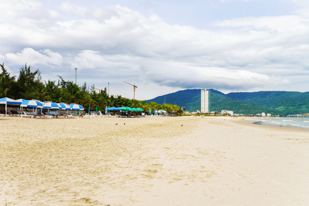 Palm shelters and people on the China Beach in Danang, Vietnam. It is also called Non Nuoc Beach. South China Sea and Marble Mountains on the background.の写真素材