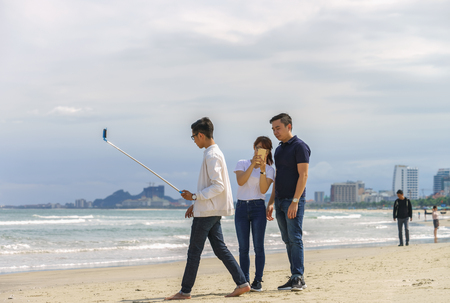 Danang, Vietnam - February 20, 2016: Young people use a selfie stick at the China Beach on Danang in Vietnamのeditorial素材