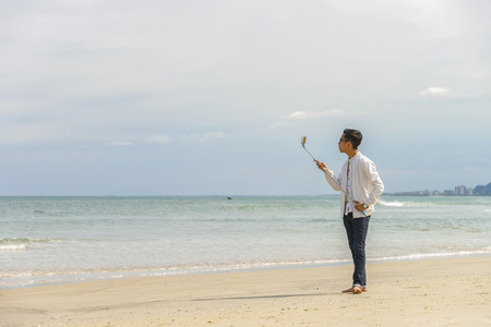Danang, Vietnam - February 20, 2016: Young fellow using a selfie stick in the China Beach in Danang in Vietnamのeditorial素材