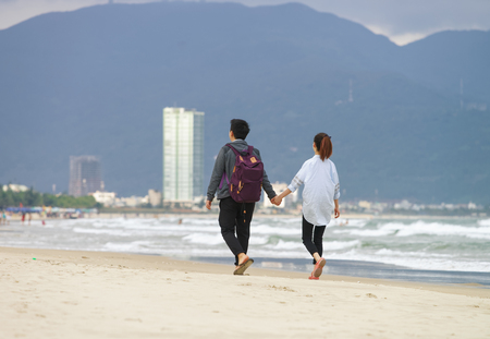 Young couple passing by and holding hands in the China Beach in Danang, in Vietnam. No faceの写真素材