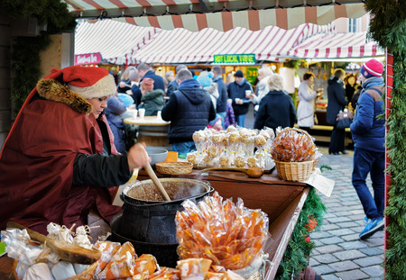 Riga, Latvia - December 26, 2015: Latvian woman in Santa hat preparing and selling homemade candies at the Riga Christmas market. There people can find traditional souvenirs, goods and warm clothes.のeditorial素材