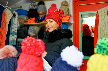 Riga, Latvia - December 26, 2015: Smiling woman selling warm clothes at the Riga Christmas market. At this stand people can find woolen hats, scarfs, gloves and mittens.のeditorial素材