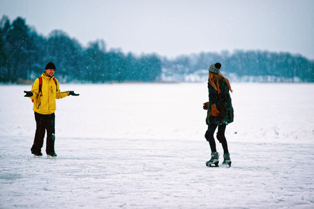 Young girl and man ice skating in the winter rink covered with snow in Trakai, in Lithuania.の写真素材