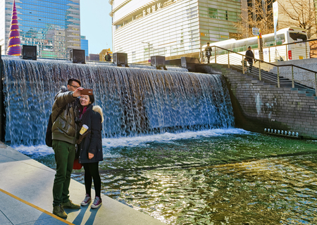 Seoul, South Korea - March 11, 2016: Korean young couple making selfie at Cheonggye stream and public walkway in Seoul, South Korea. People in the streetのeditorial素材