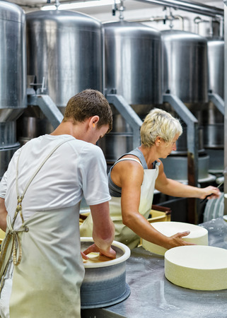 Evillers, France - August 31, 2016: Cheese-makers putting young Gruyere de Comte Cheese in the forms at the dairy in Franche Comte, Burgundy, in France.のeditorial素材