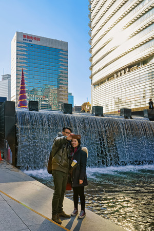 Seoul, South Korea - March 11, 2016: Korean young people making selfie at Cheonggye stream and recreation walkway in Seoul, South Korea. People in the streetのeditorial素材