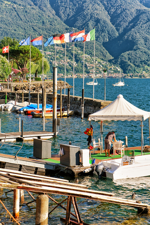 Ascona, Switzerland - August 23, 2016: Flags at the luxurious resort in Ascona on Lake Maggiore of Ticino canton, Switzerland. People on the backgroundのeditorial素材