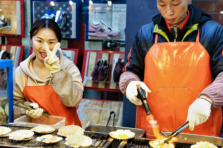 Seoul, South Korea - March 14, 2016: Male trader frying oysters for selling at Myeongdong open street market in Seoul, South Koreaのeditorial素材