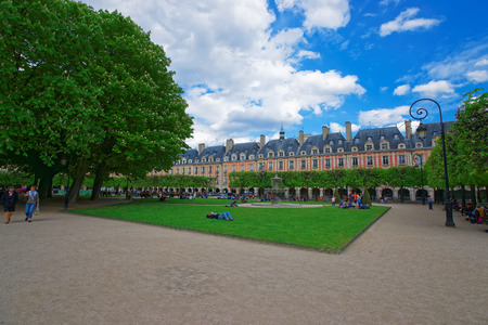 Paris, France - May 3, 2012: Place des Vosges with beautiful park and people sitting on the lawn in central Paris in France.のeditorial素材