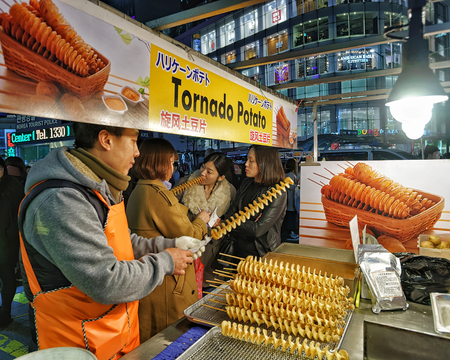 Seoul, South Korea - March 14, 2016: Seller of Potato chips and the customers at Myeongdong open street market in Seoul, South Korea. Selective focusのeditorial素材