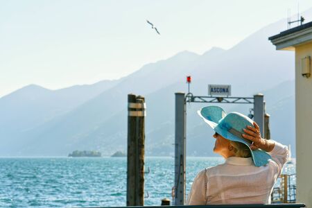 Ascona, Switzerland - August 23, 2016: Senior lady sitting on the bench at the embankment of Ascona luxurious resort on Lake Maggiore, Ticino canton, Switzerland.のeditorial素材