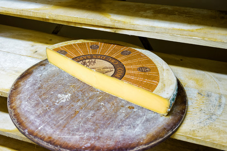 Evillers, France - August 31, 2016: Big Slice of Aging Gruyere de Cheese on wooden shelves in ripening cellar of Franche Comte dairy in Franceのeditorial素材