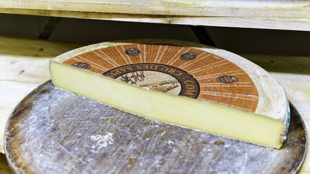 Evillers, France - August 31, 2016: Big Slice of Gruyere de Comte Aging Cheese on wooden shelves in ripening cellar of Franche Comte dairy in Franceのeditorial素材