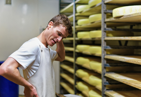 Evillers, France - August 31, 2016: Worker at storehouse of Comte Cheese in ripening cellar at Franche Comte dairy in Franceのeditorial素材