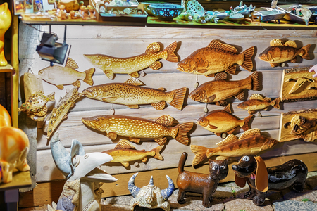 Riga, Latvia - December 26, 2015: Wooden fish looking statues displayed at the stand during the Christmas market in Riga, Latvia. Selective focus. Special filter applied.のeditorial素材
