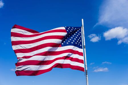 National flag of the United States in front of the sky in Boston, USA. It consists of 13 horizontal...