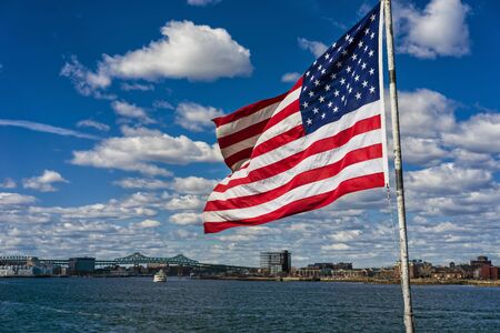 City skyline and flag of the United States of America in Boston, USA. It is one of the main symbols of the country and consists of 13 horizontal stripes with 50 small stars for each state.の写真素材