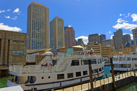 Boston, USA - April 28, 2015: Tall buildings and moored ferry boats with people  in the bay in Boston, USA. The city is surrounded by various water facilitiesのeditorial素材