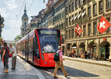 Bern, Switzerland - August 31, 2016: People and running tram at Spitalgasse street with shopping area in old city center of Bern, Switzerland. Steeple of Holy Spirit Church on the backgroundのeditorial素材