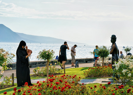 Vevey, Switzerland - August 27, 2016: People at Charlie Chaplin statue at Geneva Lake, Vevey, Vaud canton, Switzerland. Alps mountains on the backgroundのeditorial素材