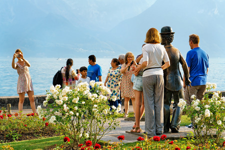 Vevey, Switzerland - August 27, 2016: People at Charlie Chaplin statue at Geneva Lake in Vevey, Vaud canton, Switzerland. Alps mountains on the backgroundのeditorial素材