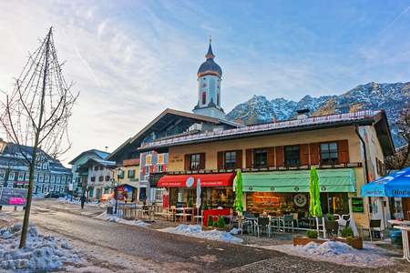 Garmisch-Partenkirchen, Germany - January 6, 2015: Steeple of St Martin church in the street in Garmisch-Partenkirchen old town, Germany. People on the backgroundのeditorial素材