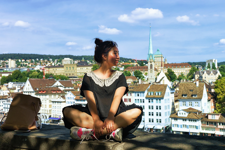 Zurich, Switzerland - September 2, 2016: Asian girl sitting on Lindenhof hill in Zurich, Switzerland. Limmatquai and Predigerkirche on the background.のeditorial素材