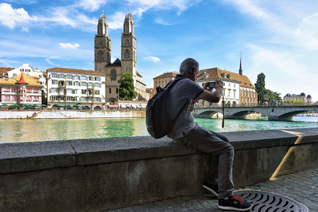 Zurich, Switzerland - September 2, 2016: Man taking photo at Limmatquai and Grossmunster Church in Zurich, Switzerland.のeditorial素材