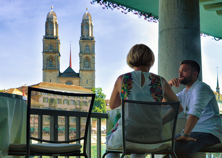 Zurich, Switzerland - September 2, 2016: Couple relaxing at the street restaurant at Limmatquai and Grossmunster Church in Zurich, Switzerland.のeditorial素材
