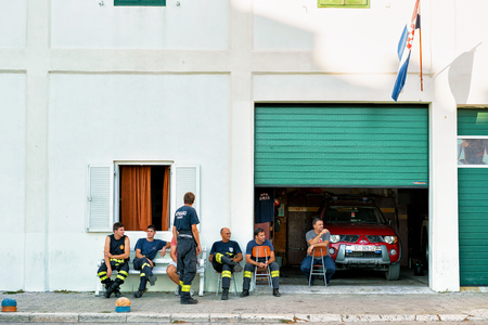 Omis, Croatia - August 18, 2016: Firemen having a break and sitting at fire station in Omis, Croatia