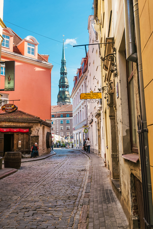 Riga, Latvia - September 3, 2014: Street with people and spire of St Peter Church in the historical center in the old town of Riga, Latvia.のeditorial素材