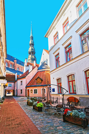 Street cafe and spire of St Peter Church in the historical center in the old town of Riga, Latvia.のeditorial素材