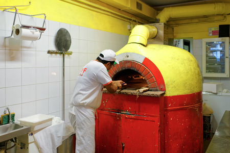 Florence, Italy - October 15, 2016:  Chef preparing pizza in oven at pizzeria in Florence, Tuscany, Italy.のeditorial素材