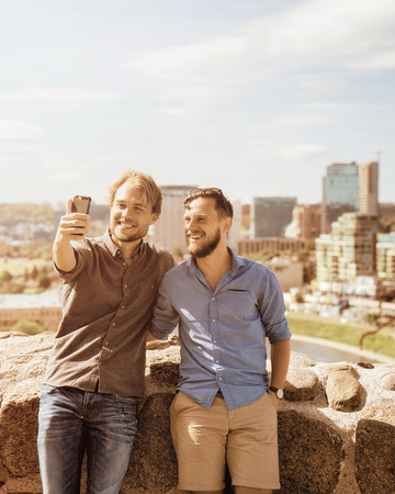 Happy young caucasian buddies making selfie in front of city skyline as travel and friendship conceptの写真素材